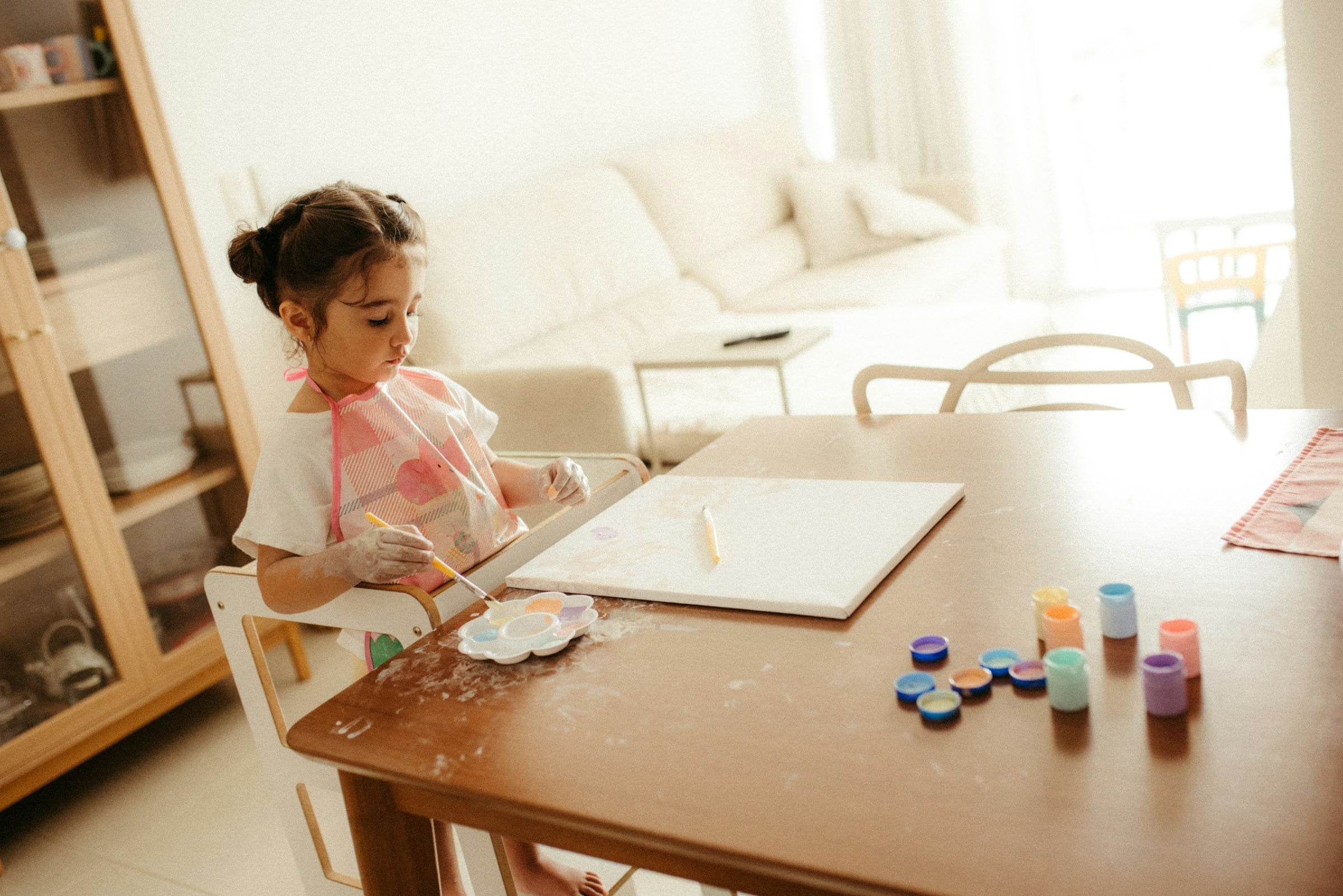 Young girl painting at a table with bright paints